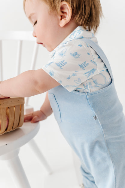 Child wearing a light blue outfit with a white background