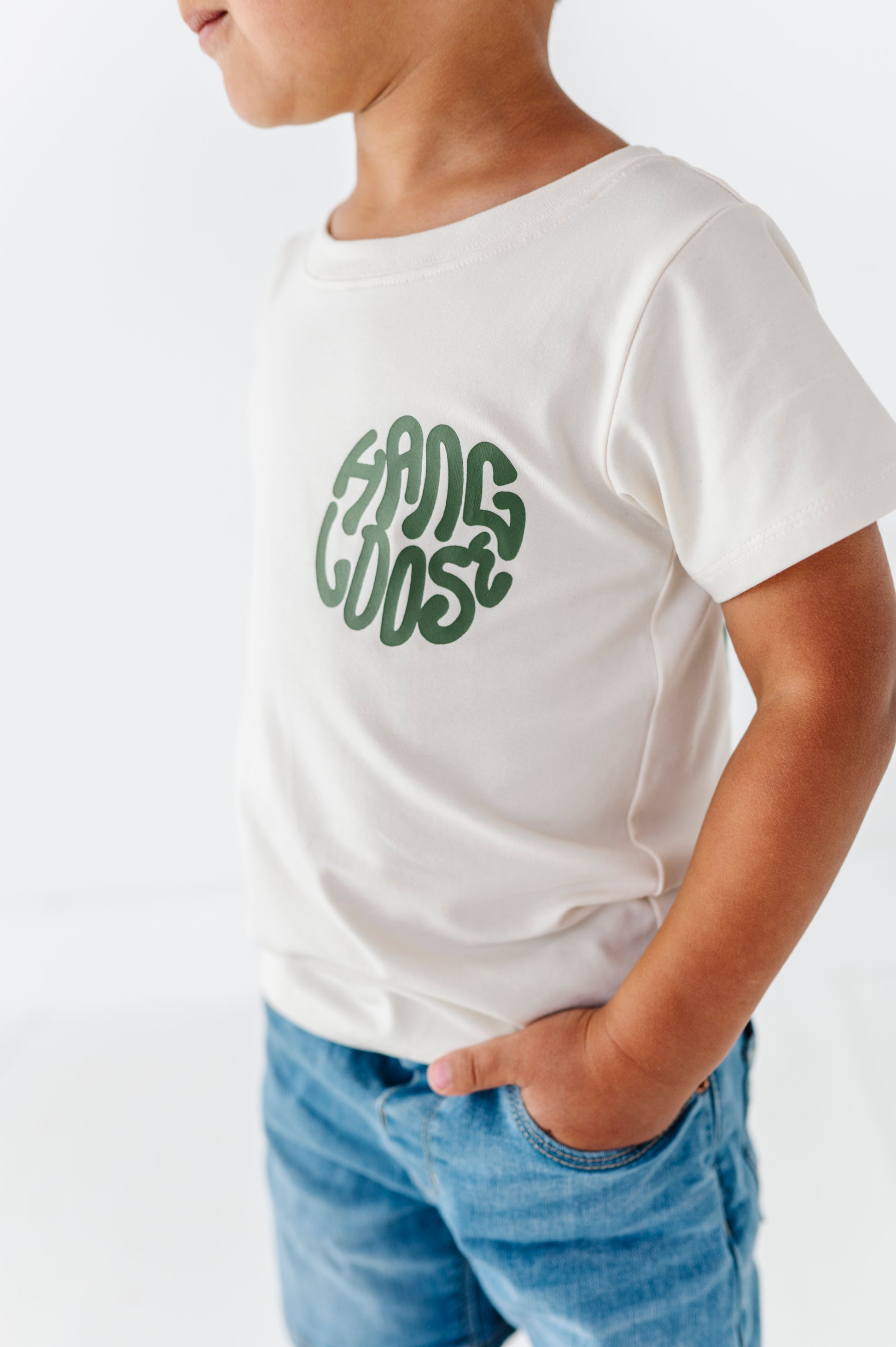 Child wearing a white t-shirt with green text on a plain background