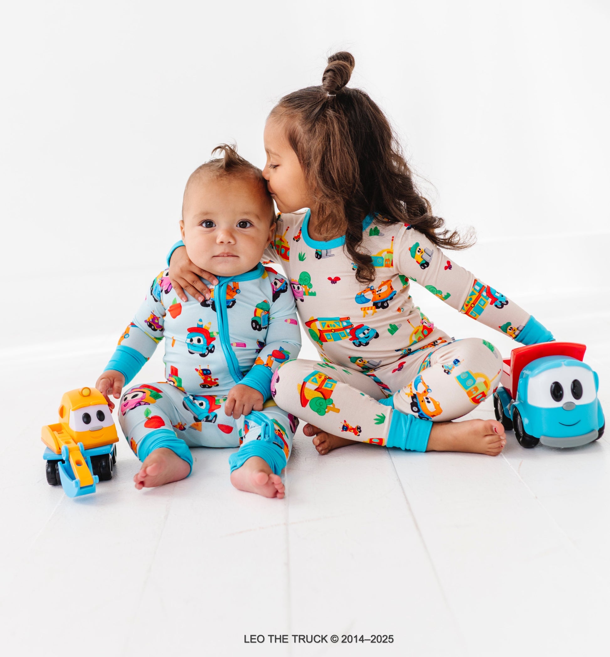 Two children wearing colorful Leo the Truck bamboo pajamas on a white background.