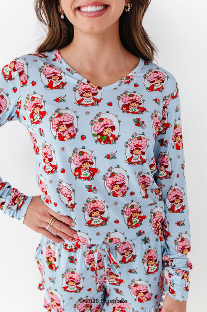 Woman wearing a light blue Strawberry Shortcake™ pajama set on a white background