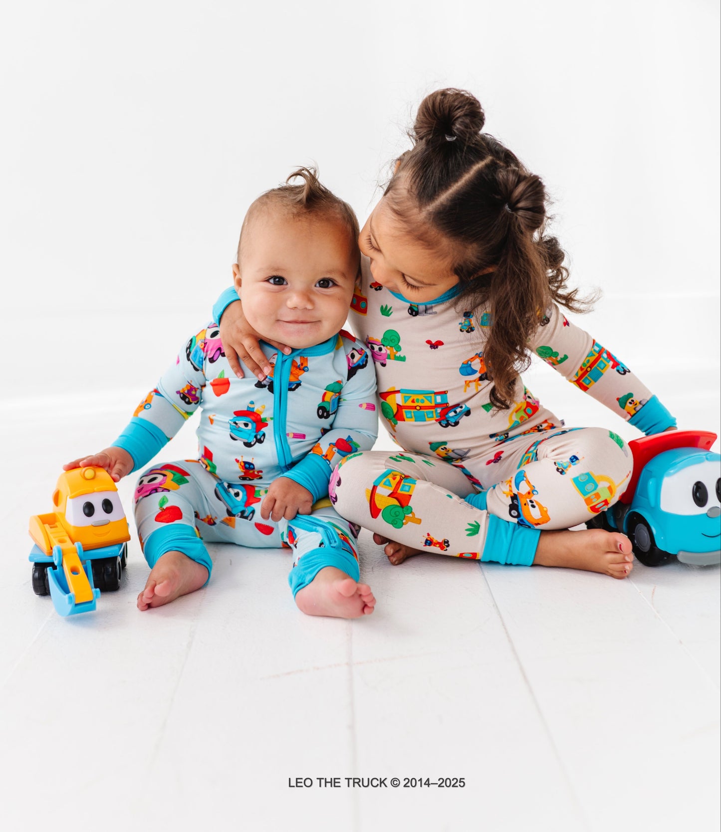 Two children wearing colorful Leo the Truck bamboo pajamas on a white background.