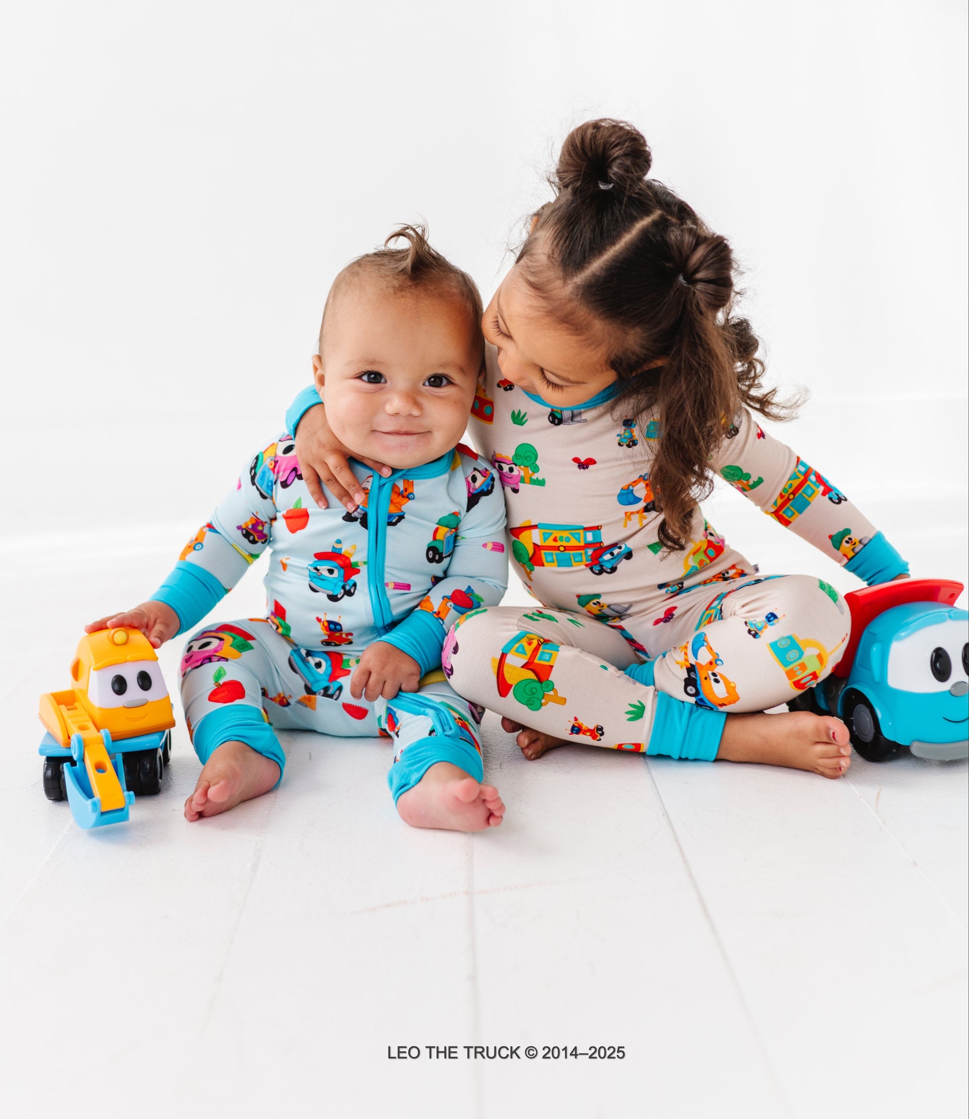 Two children wearing colorful Leo the Truck bamboo pajamas on a white background.