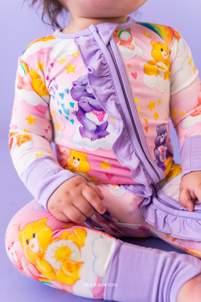 Child wearing a colorful Care Bears™ bamboo outfit on a purple background