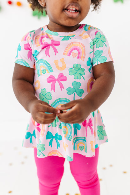 Close-up shot of a child wearing a lucky charm bamboo cotton peplum top with hot pink bamboo leggings 