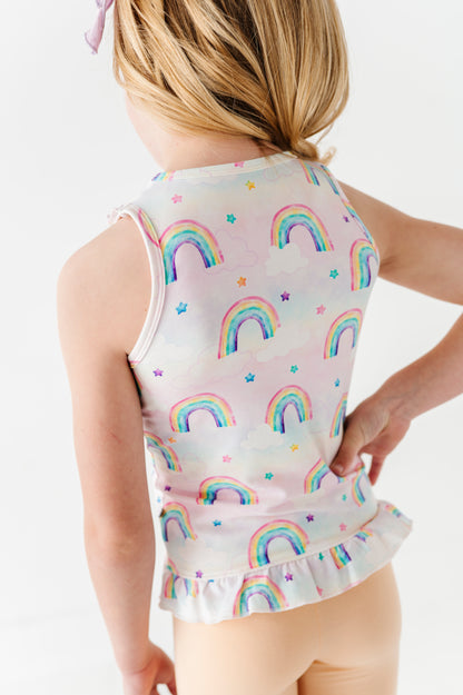 Child wearing a sleeveless bamboo cotton peplum top with watercolor rainbow pattern on a plain background