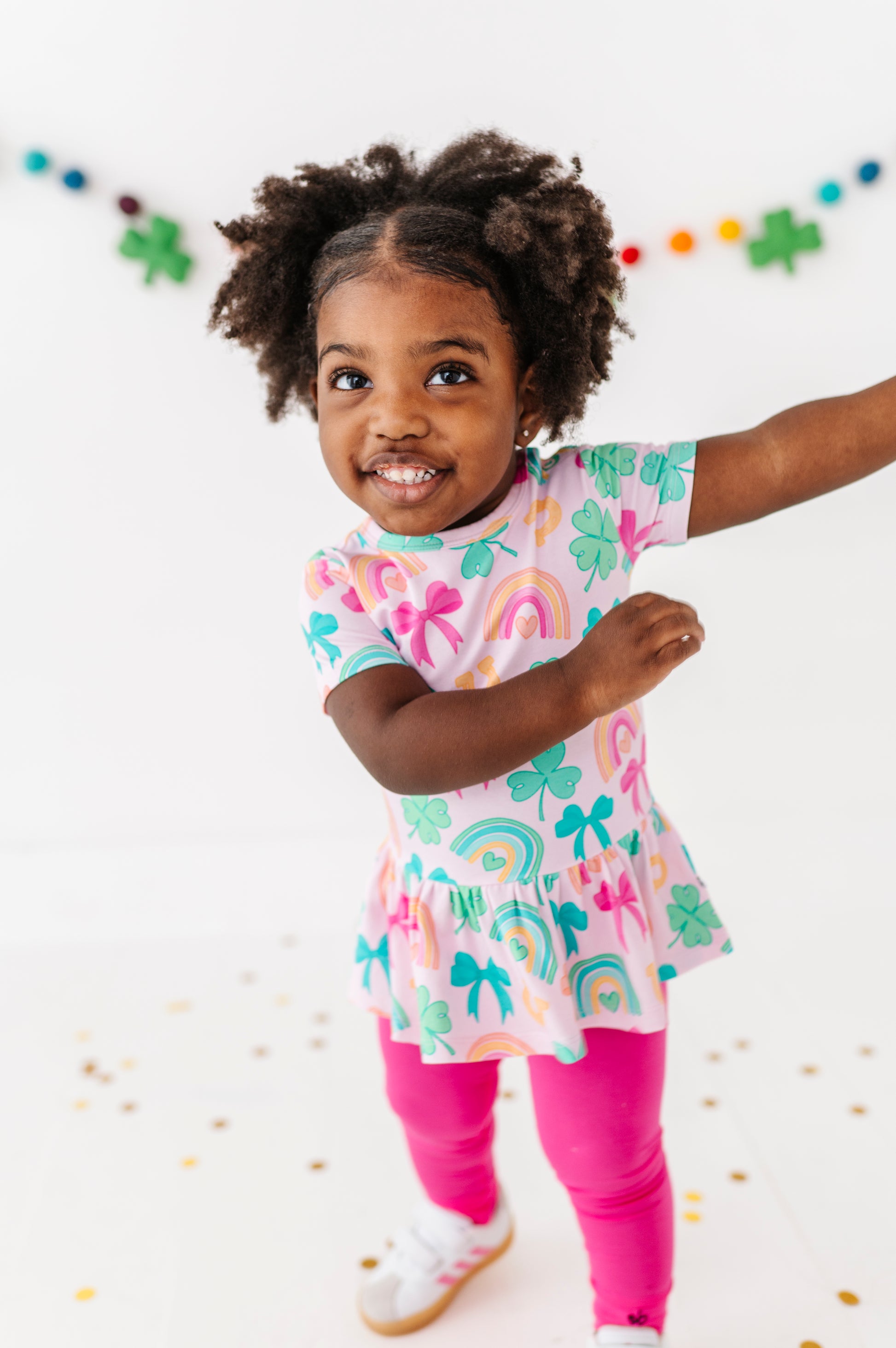 Child wearing a colorful bamboo cotton peplum top against a white St. Patrick's Day background