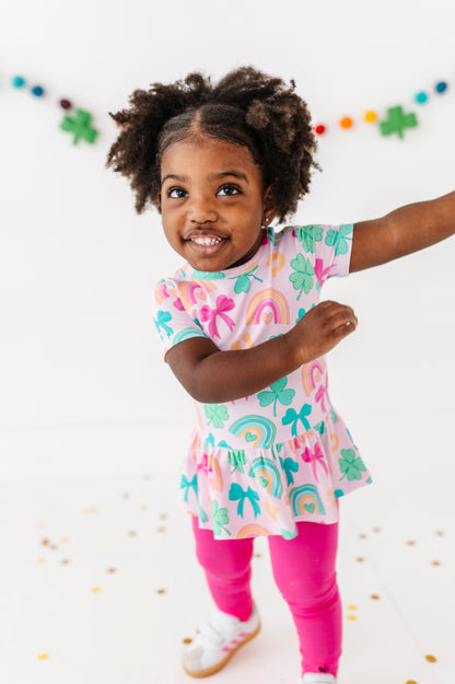 Child wearing a colorful bamboo cotton peplum top against a white St. Patrick's Day background