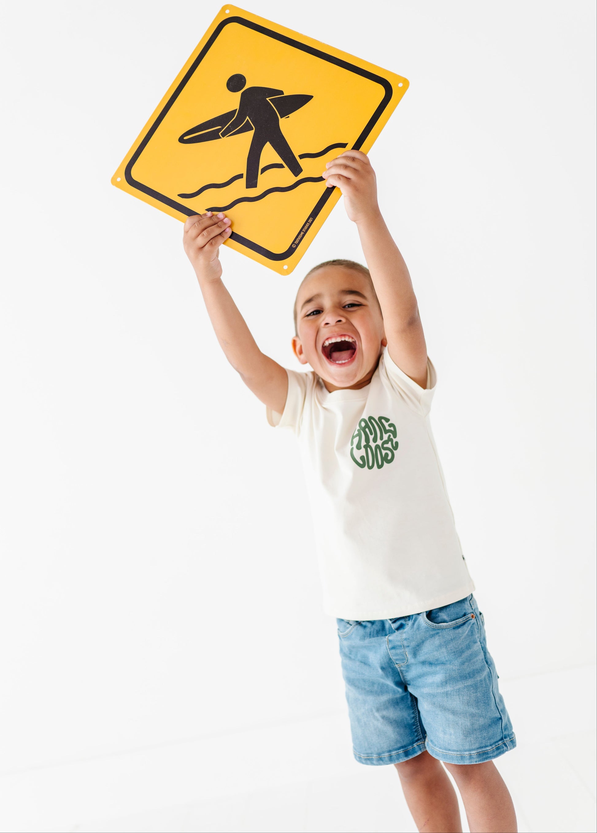 Child holding a yellow surf sign against a white background