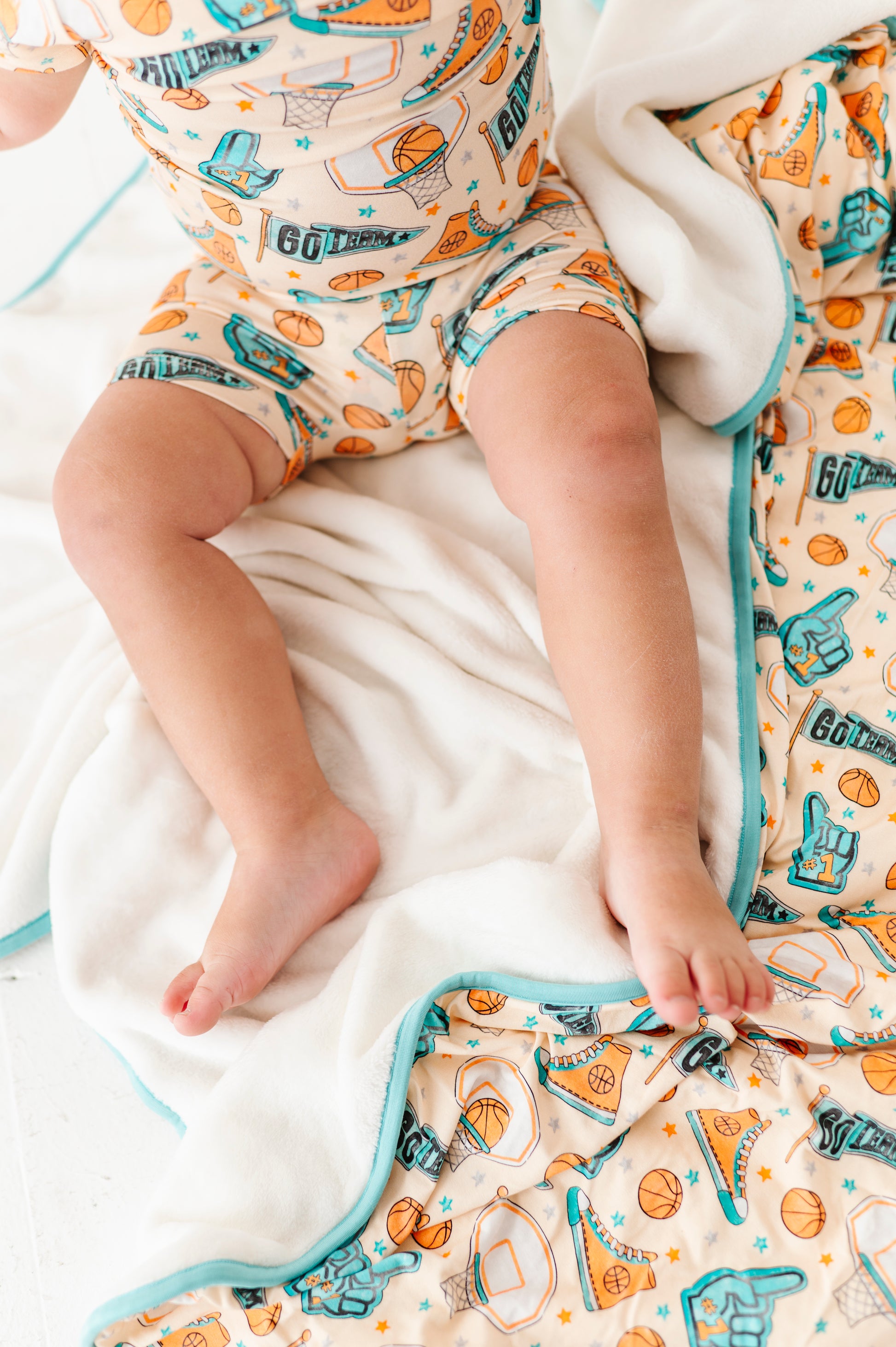 Baby sitting on a blanket with a sports themed pattern