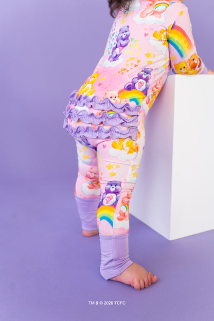 Child wearing colorful pajama set with ruffled pants on a purple background