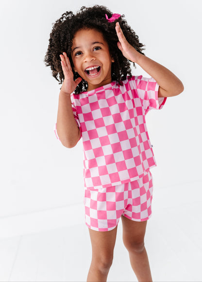 Child wearing a pink and white checkered outfit on a white background