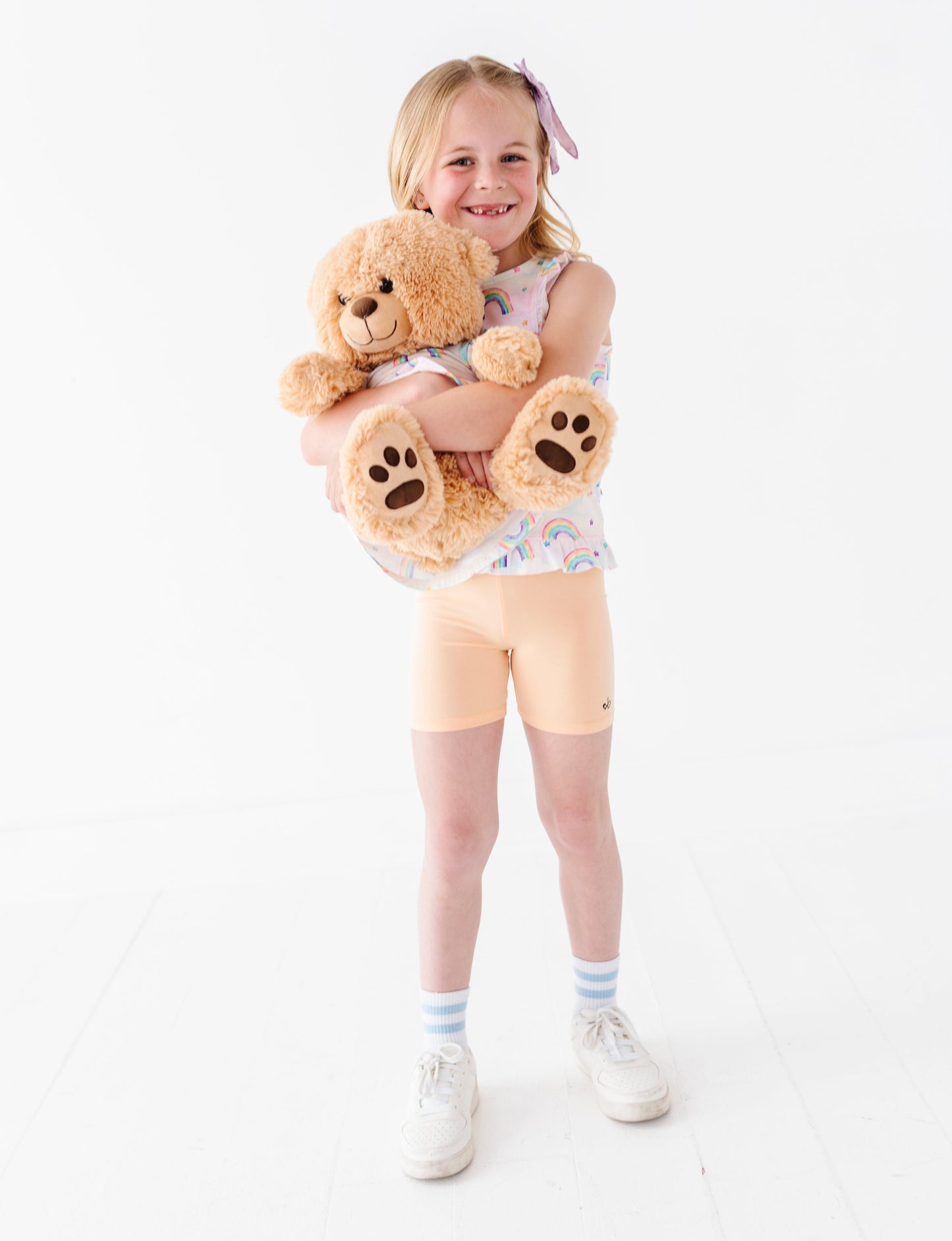 Young girl and her teddy bear wearing matching watercolor rainbow bamboo styles 