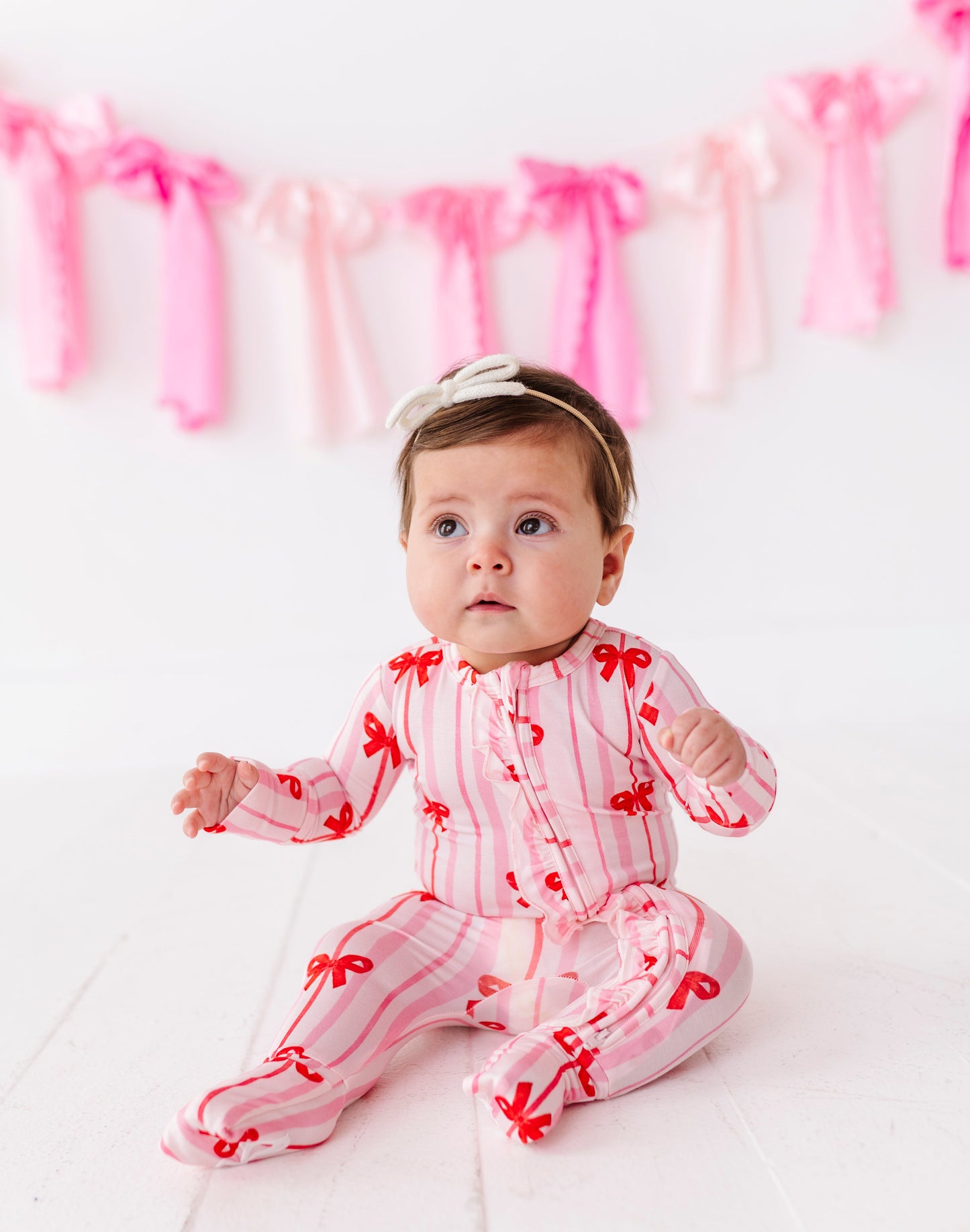 Infant sitting in Ruby Ribbons ruffle convertible romper with fold-over foot cuffs