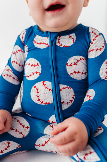 Baby wearing a blue bamboo romper with baseball pattern