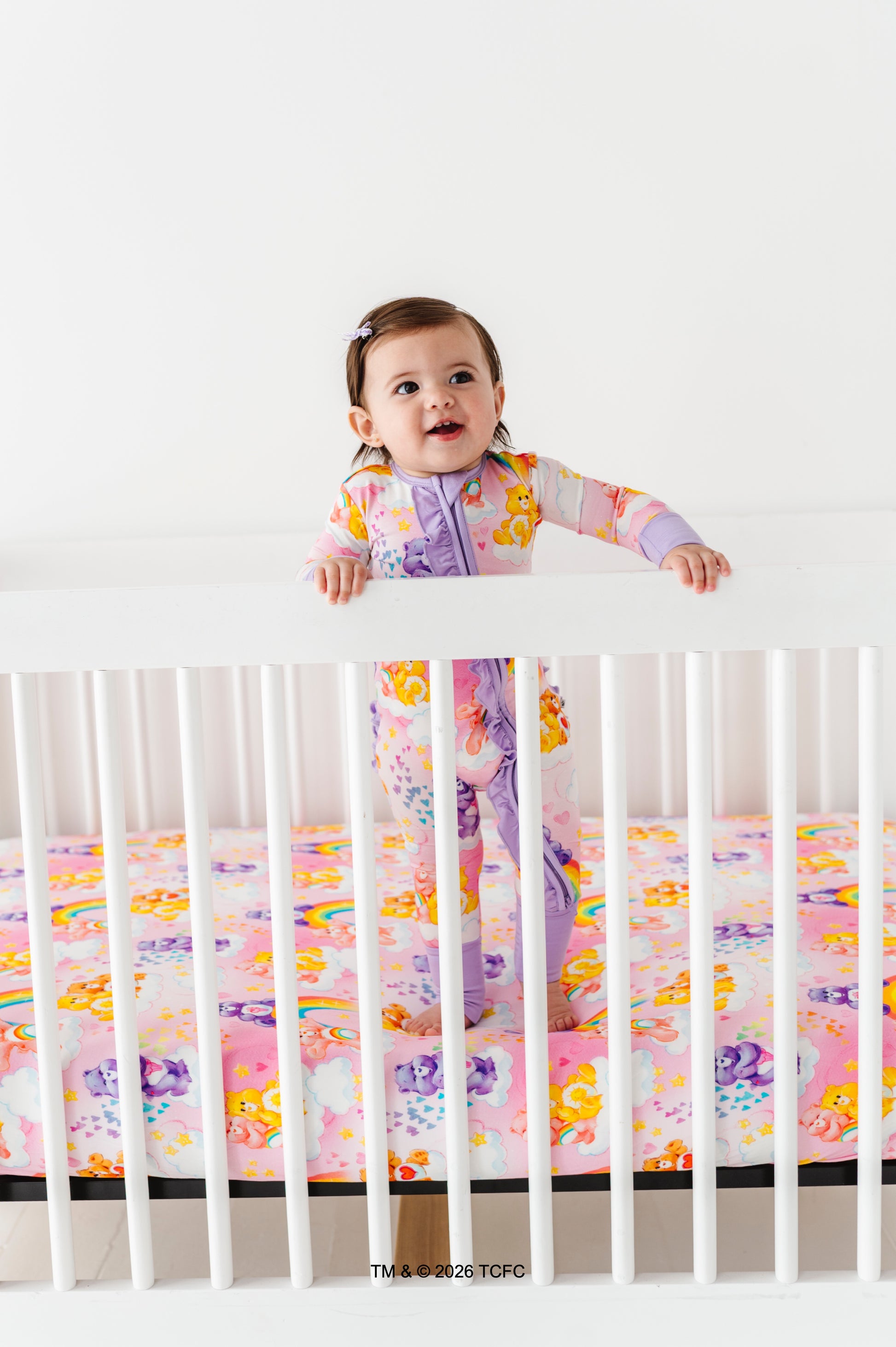 Child in a crib with colorful Care Bears™ bamboo bedding and a white background