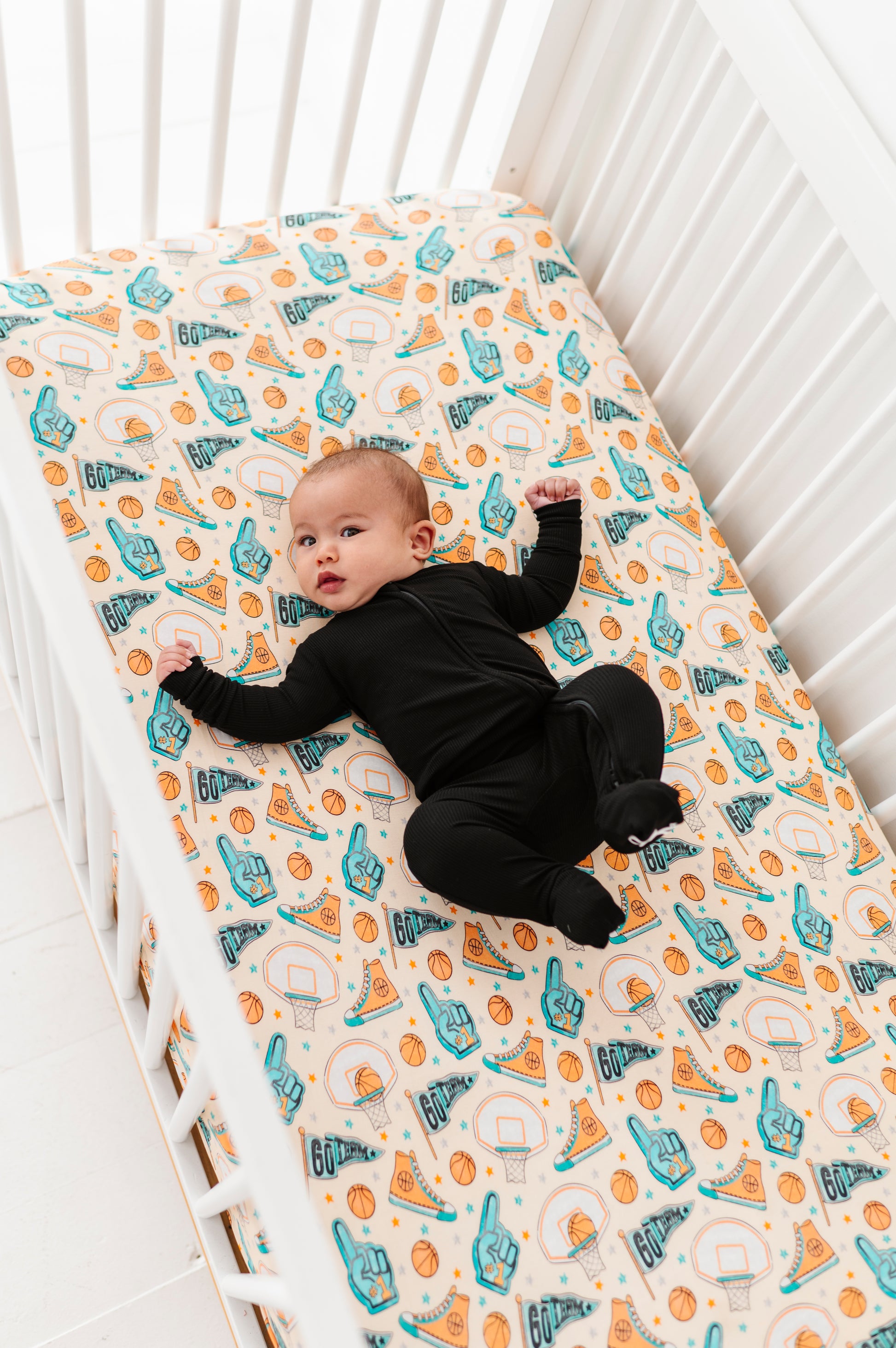 Baby lying on a bamboo crib mattress with sports-themed pattern