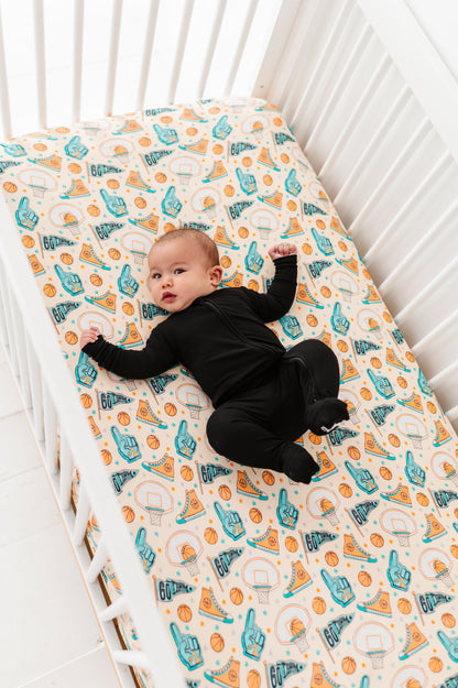 Baby lying on a bamboo crib mattress with sports-themed pattern
