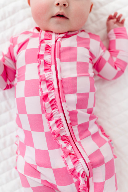 Baby wearing a pink and white checkered bamboo onesie on a white blanket