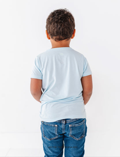 Child wearing a light blue t-shirt and blue jeans on a white background