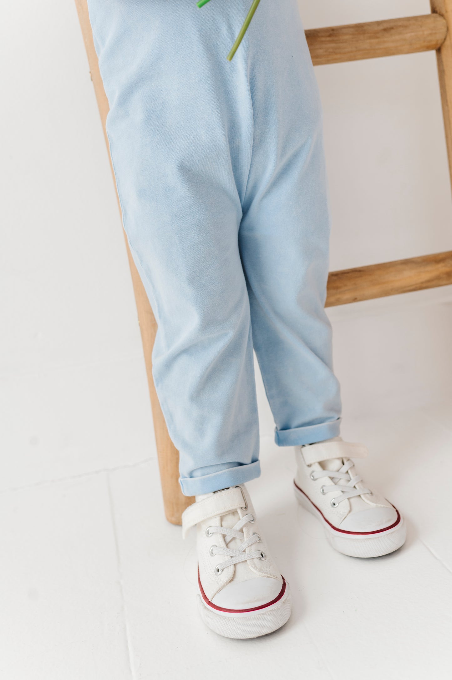 Person wearing light blue jeans and white sneakers with red soles on a white background