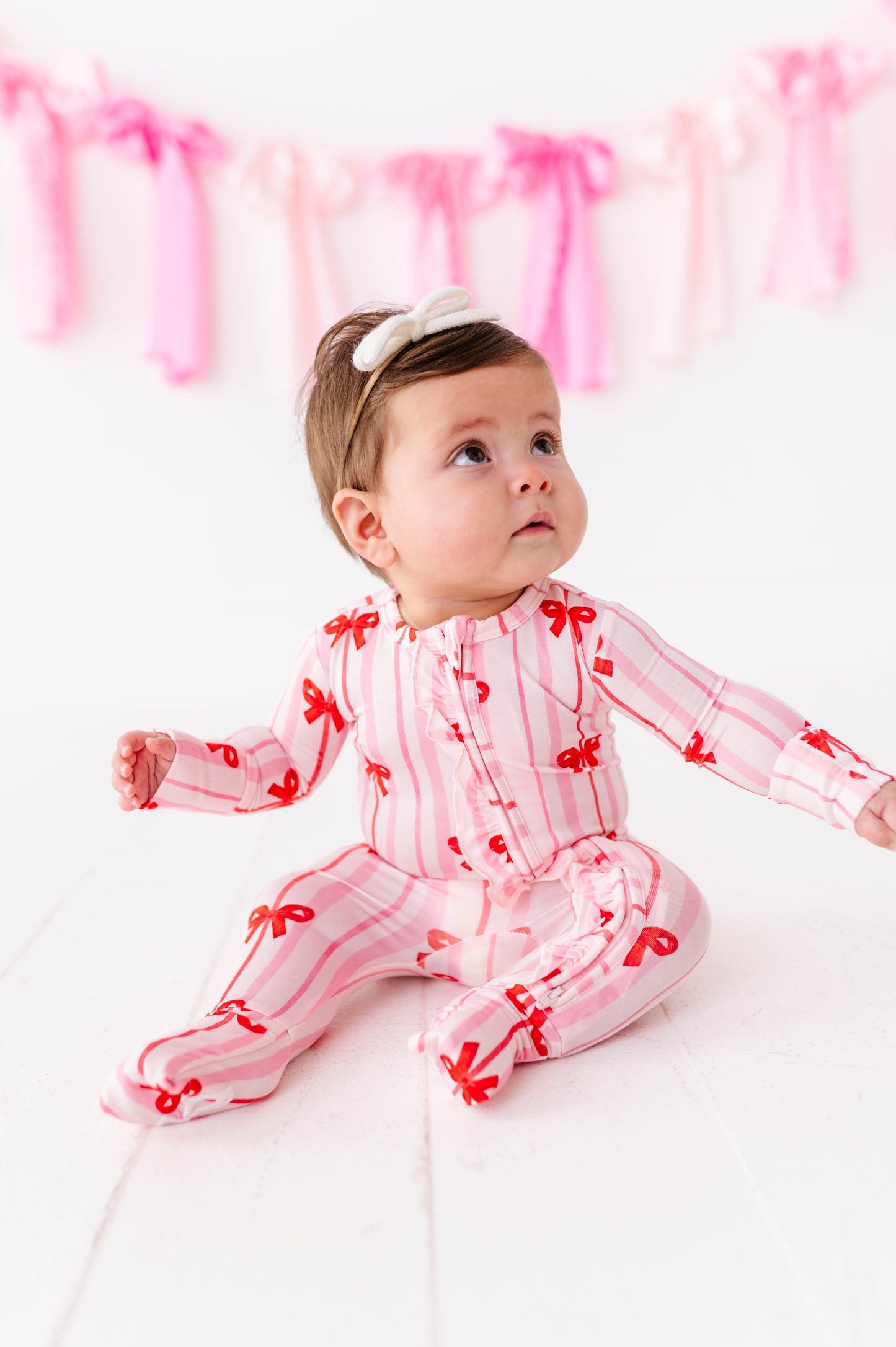 Baby girl in pink striped bamboo romper with red ribbon bows and front ruffle