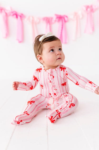 Baby girl in pink striped bamboo romper with red ribbon bows and front ruffle