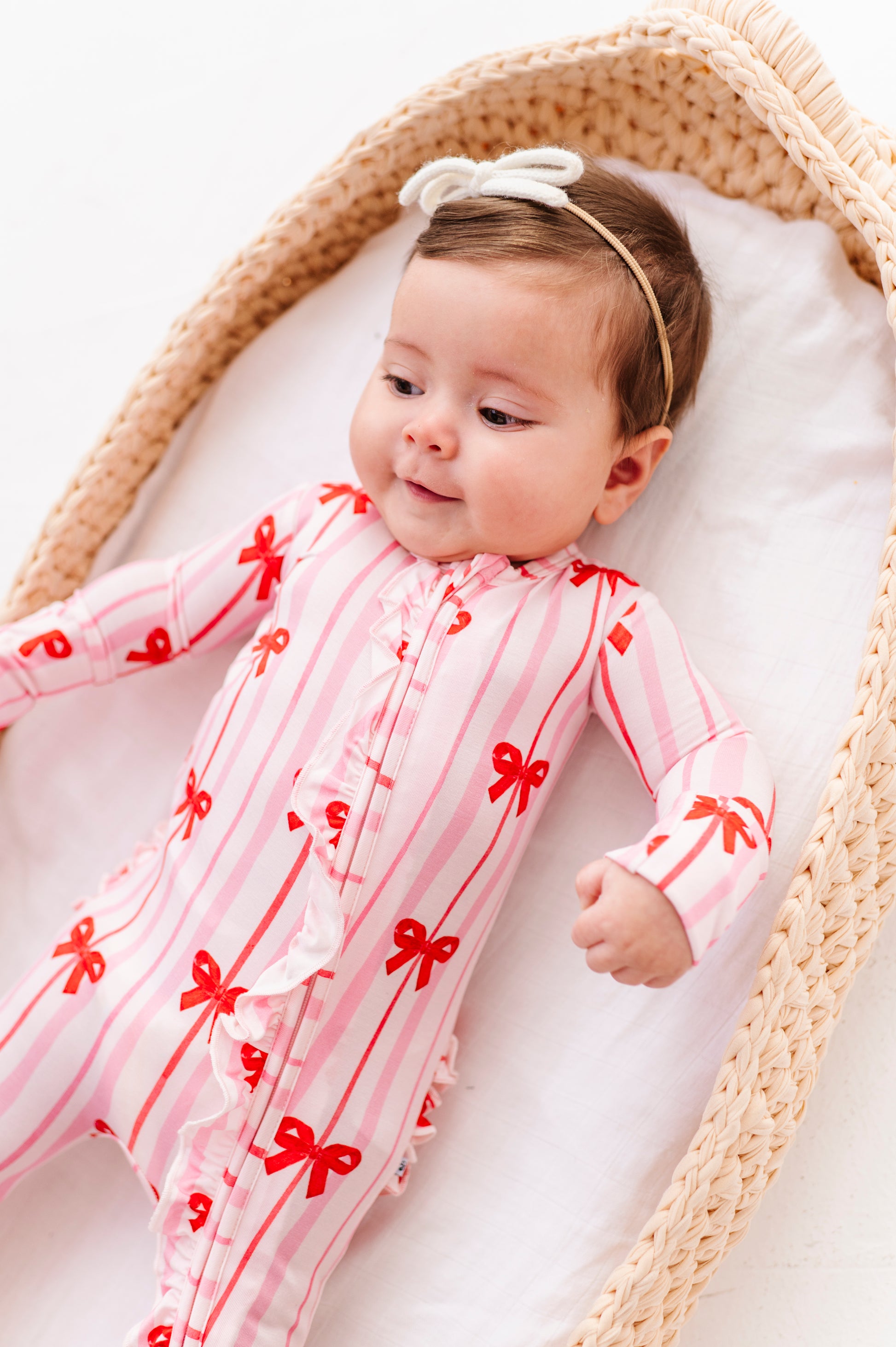 Infant lounging in Ruby Ribbons ruffle convertible romper with bow stripe print