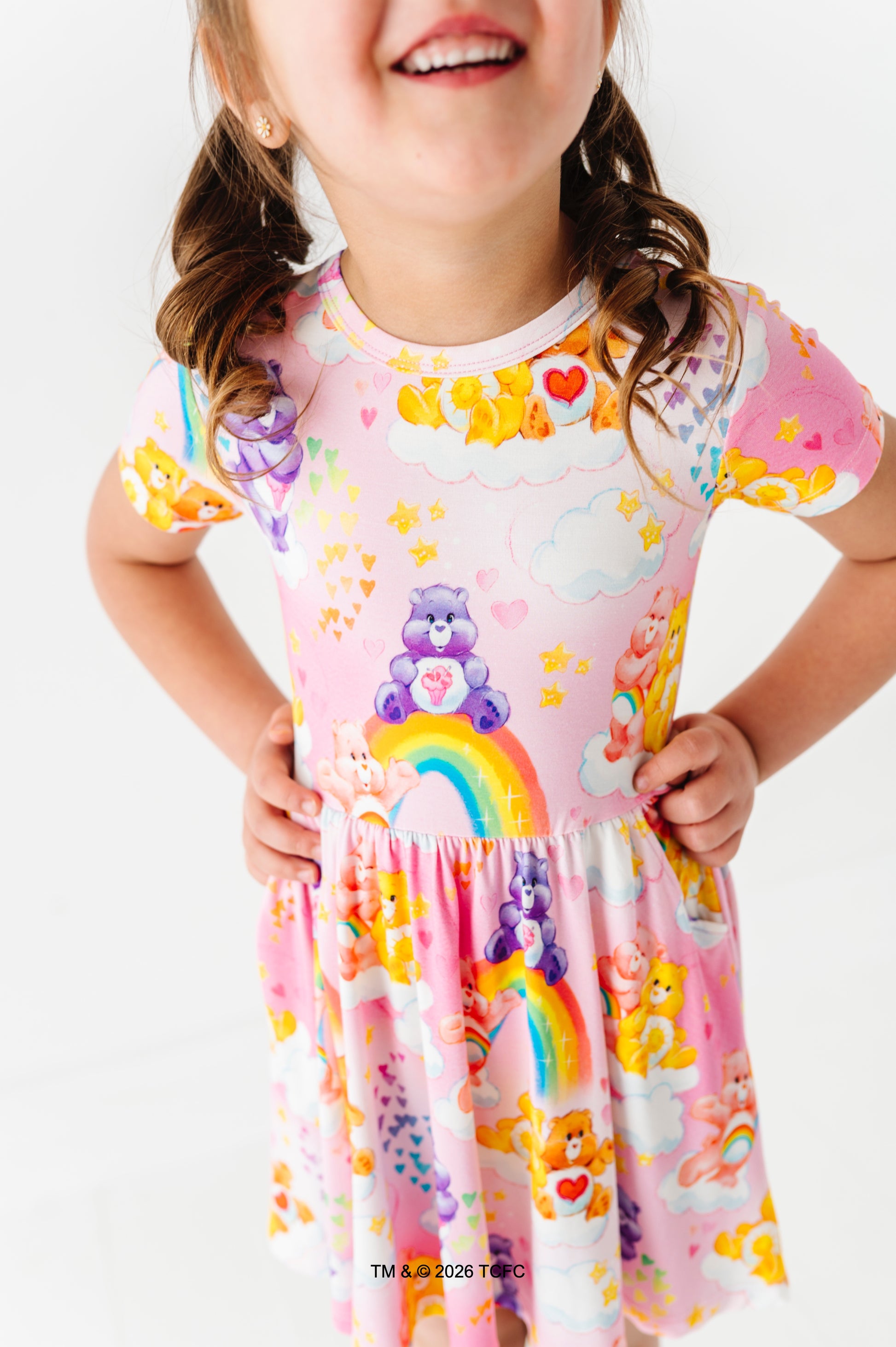 Child wearing a colorful Care Bears™ bamboo dress on a white background