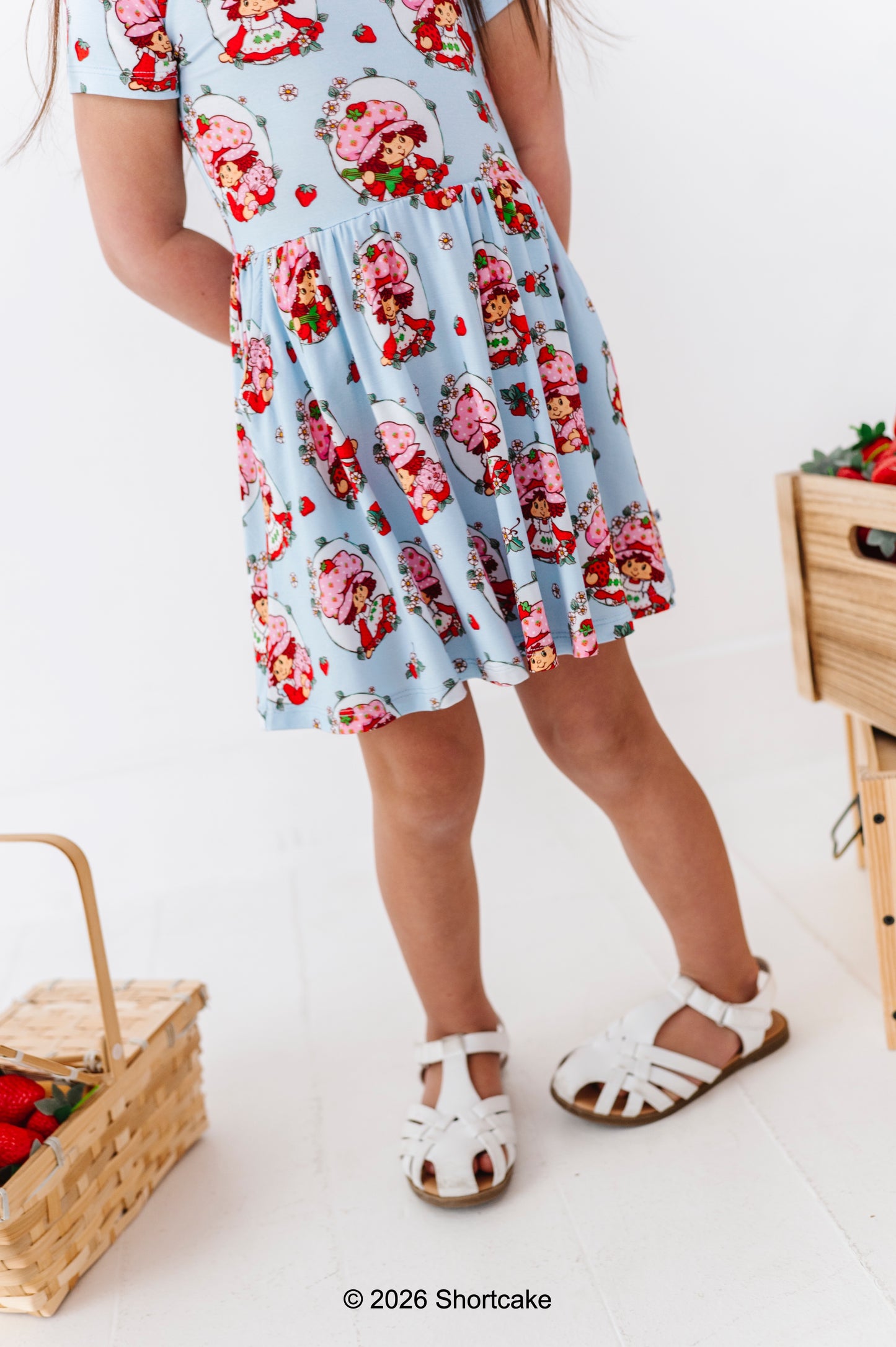 Little girl wearing a Strawberry Shortcake™ dress with a white background