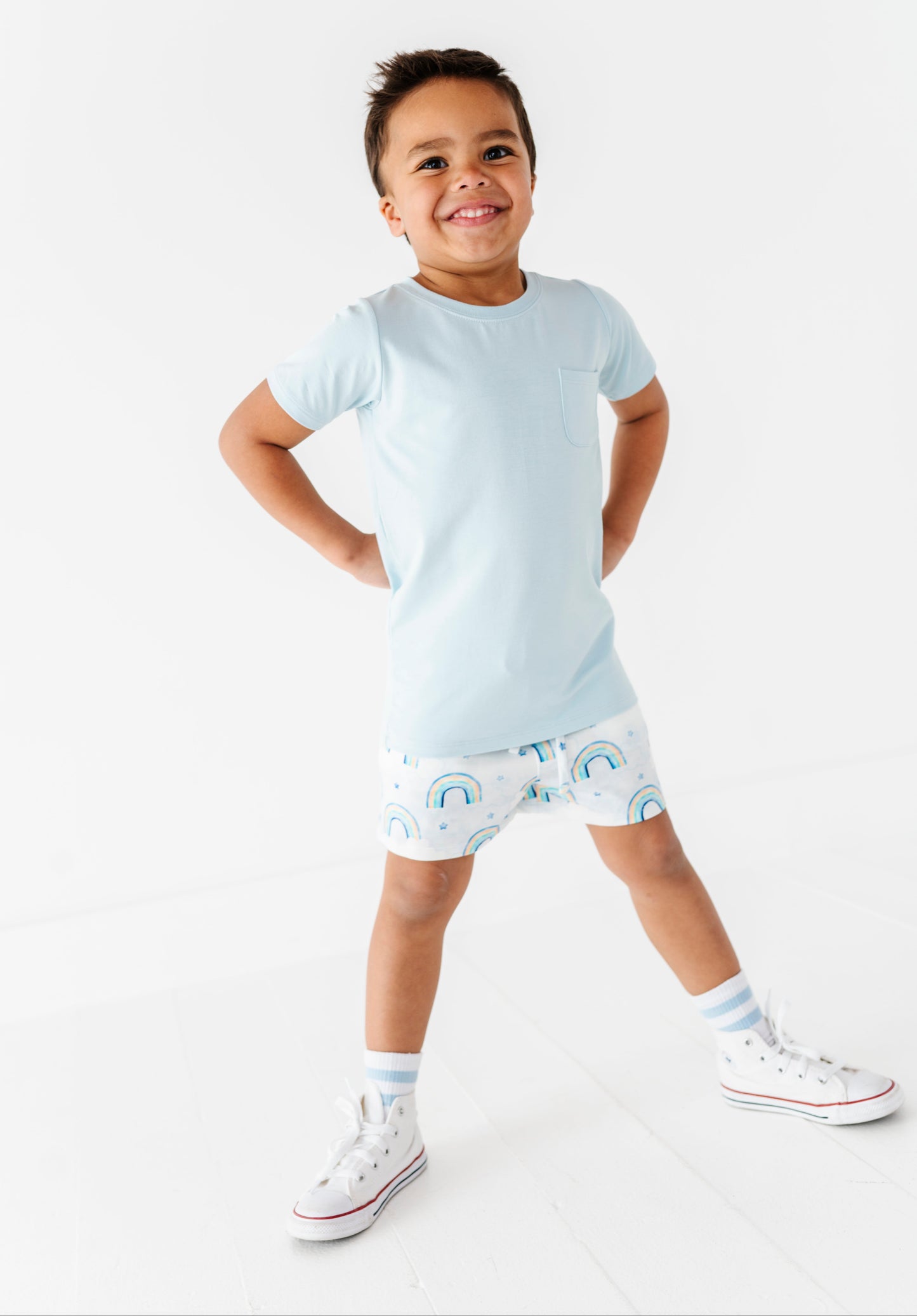 Child wearing a light blue t-shirt and patterned shorts on a white background