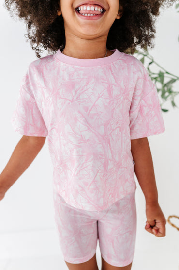 Child wearing a pink tie-dye outfit with a white background