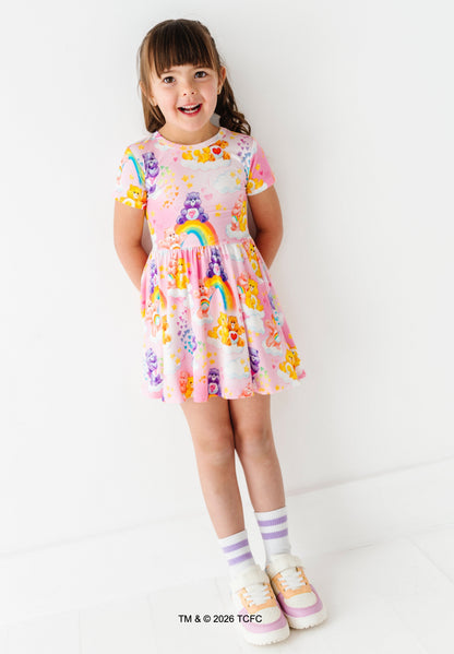 Young girl wearing a colorful dress with Care Bears™ design on a white background.