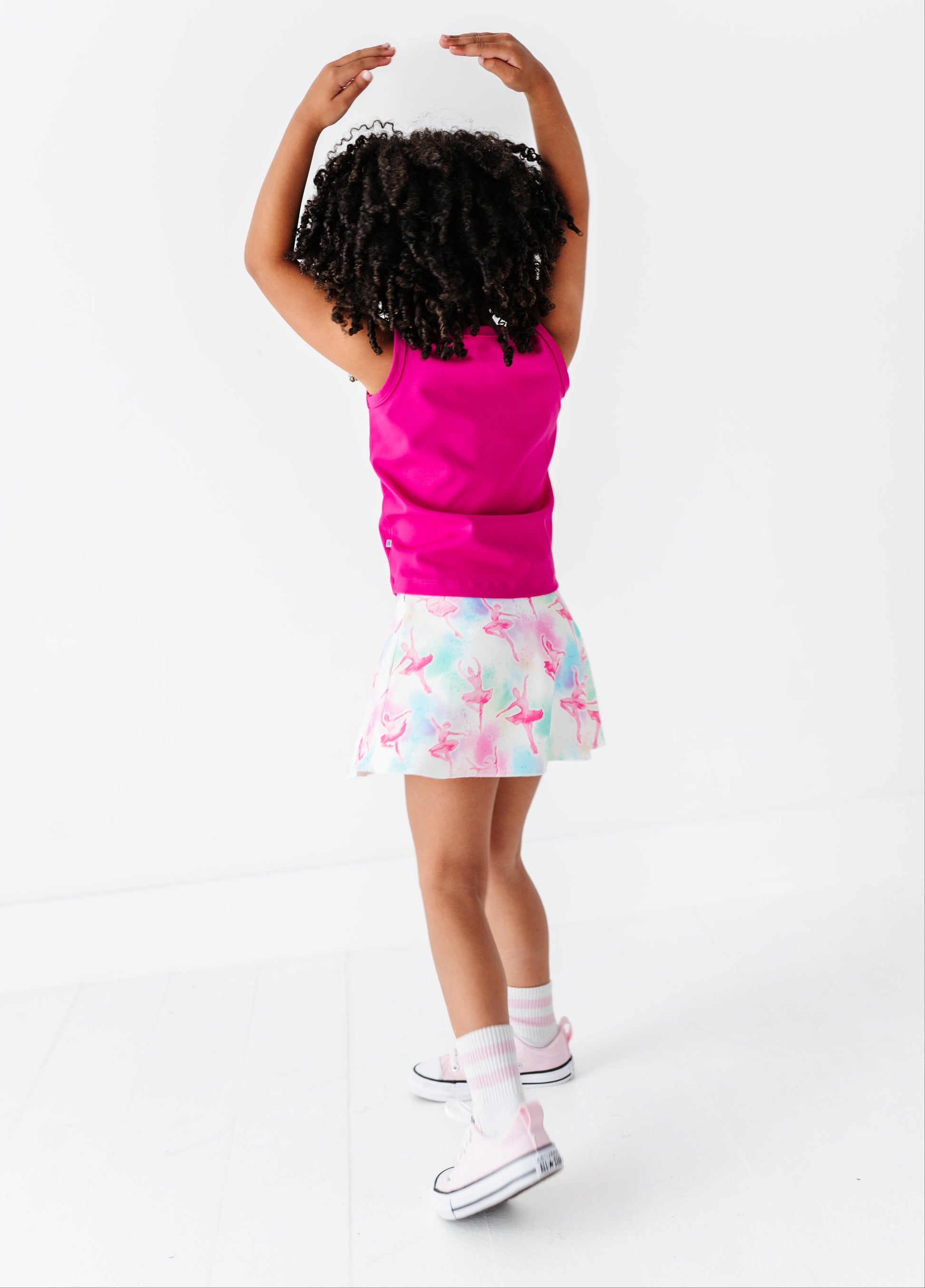 Child wearing a pink top and colorful skirt on a white background