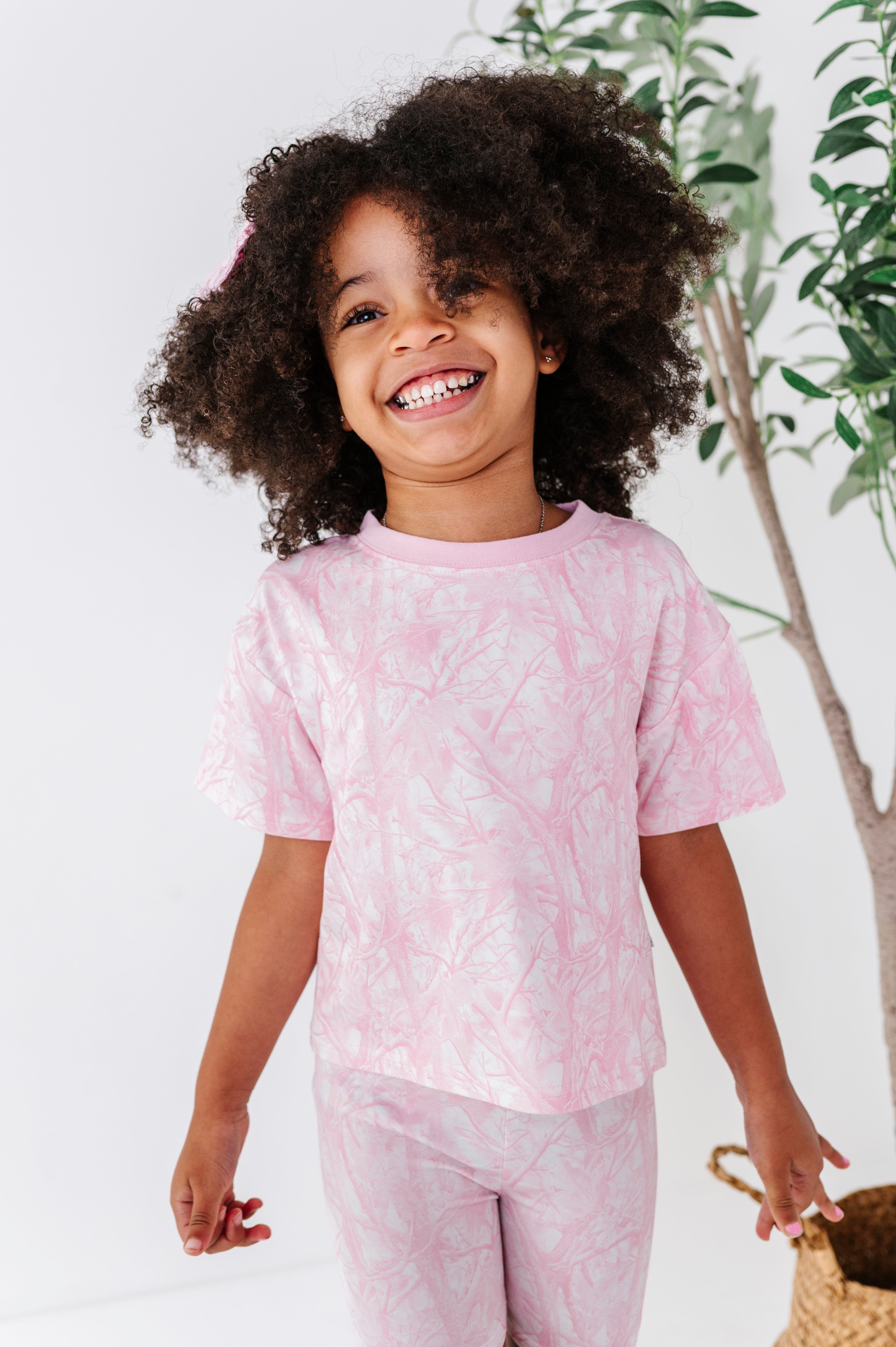 Child wearing pink camo clothes with a white background