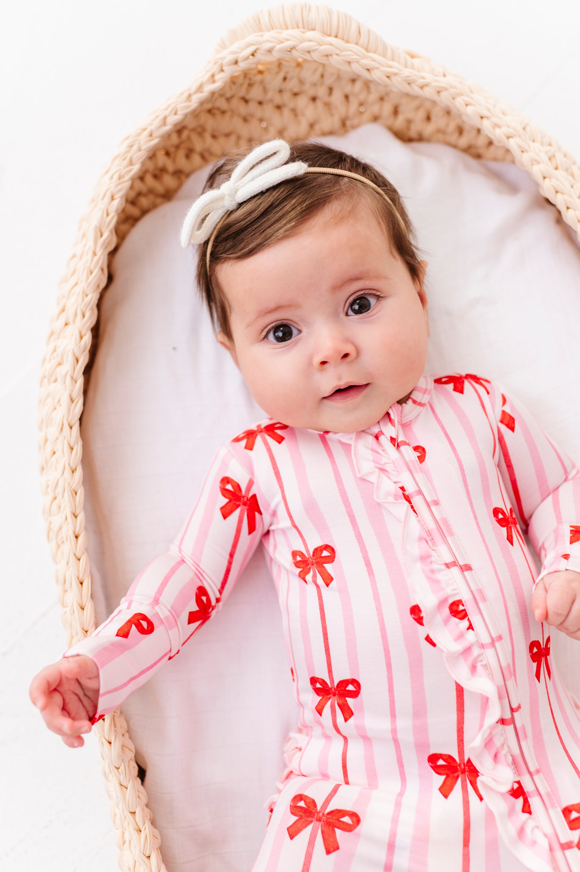 Baby girl in pink striped bamboo romper with red ribbon bows and front ruffle