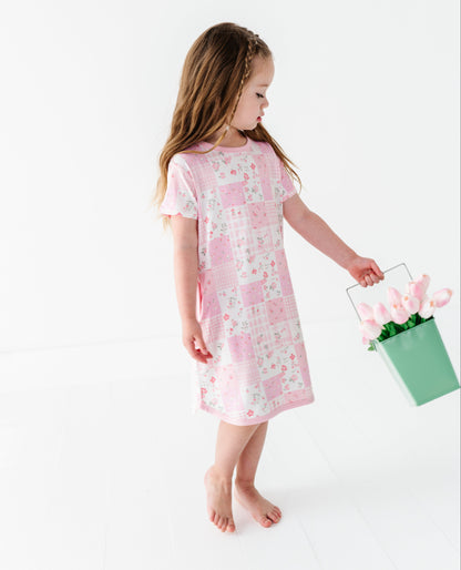 Young girl in a pink floral bamboo gown holding a green basket with tulips on a white background