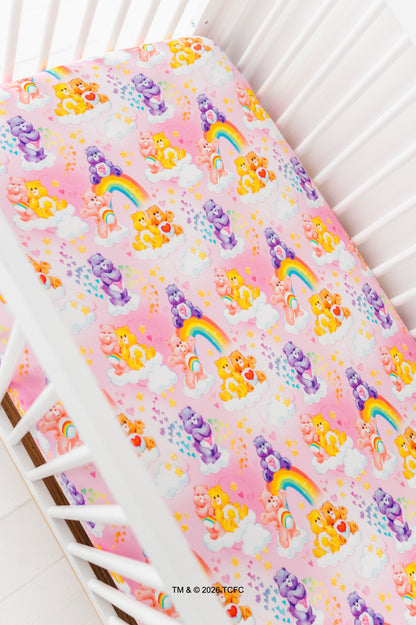 Crib sheet with colorful Care Bears™ design on a white crib
