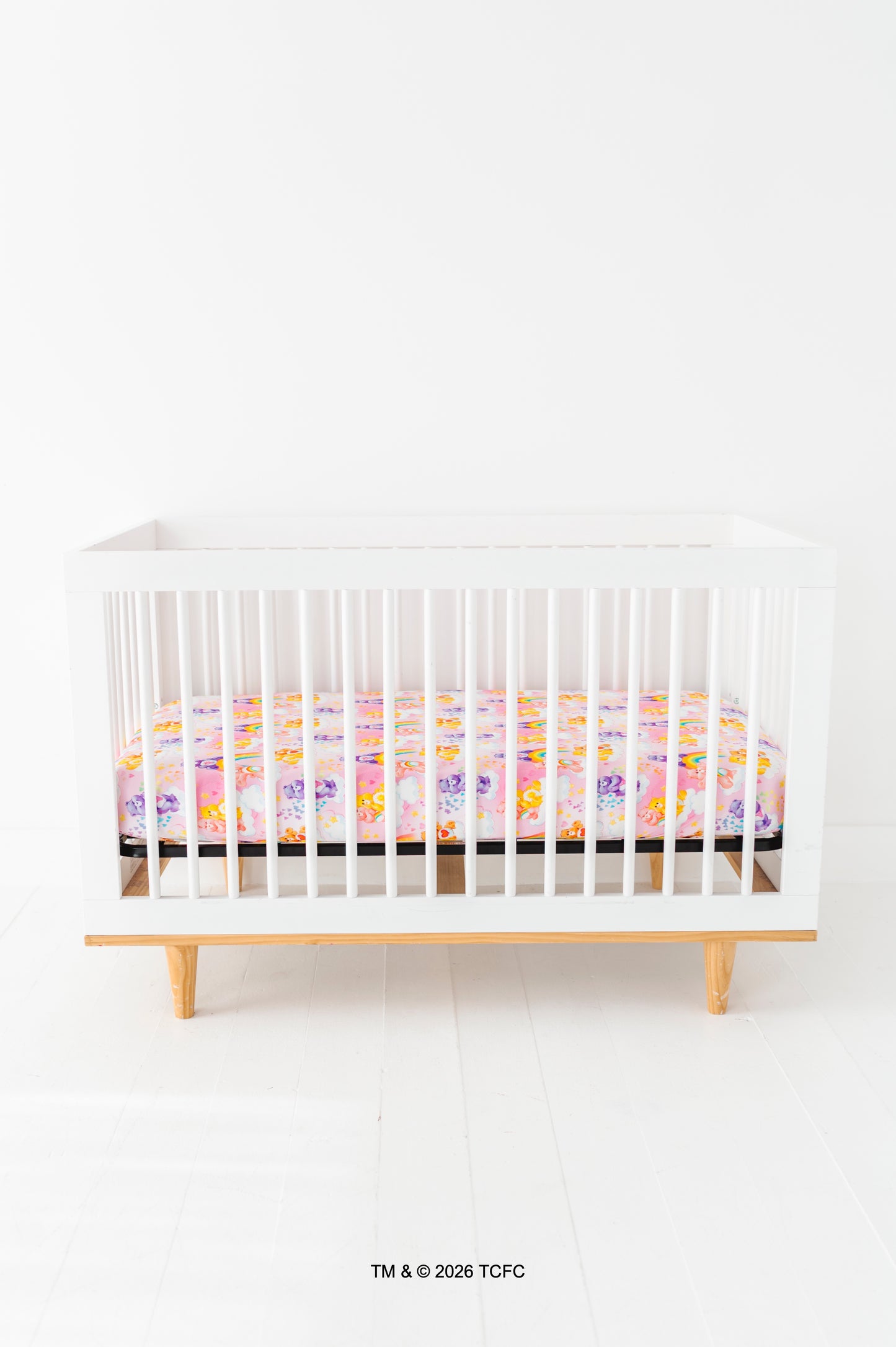 White crib with a colorful Care Bears™ crib sheet on a white background