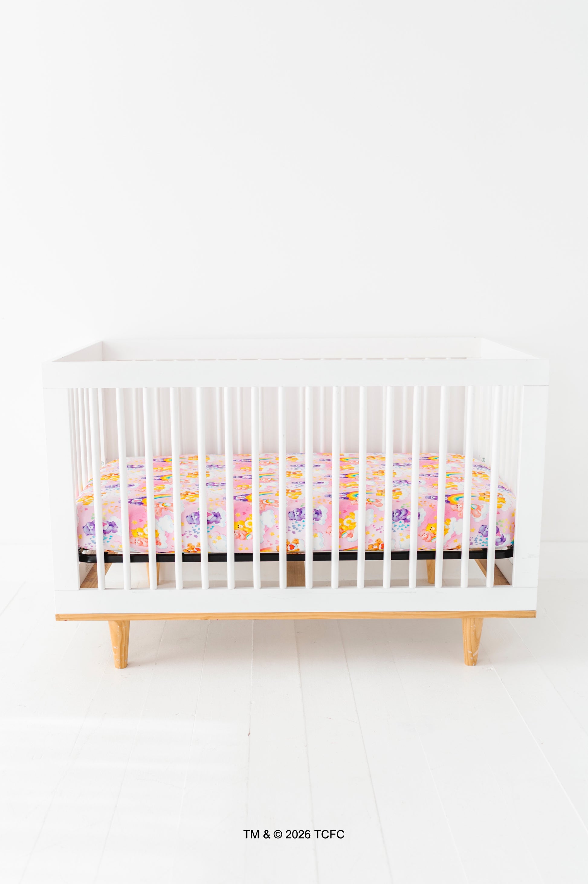 White crib with a colorful Care Bears™ crib sheet on a white background