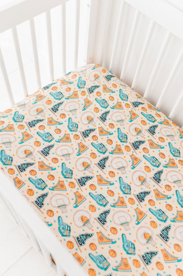 Bamboo crib sheet with sports-themed pattern on a white crib