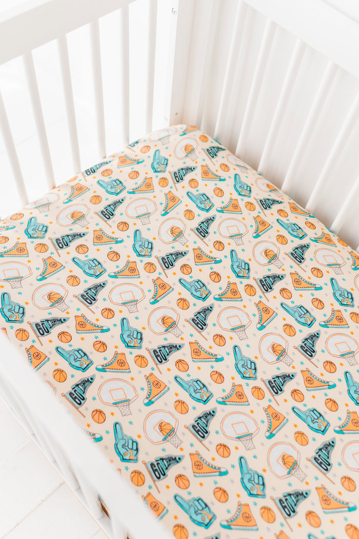 Bamboo crib sheet with sports-themed pattern on a white crib