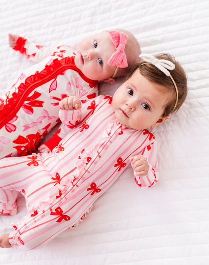 Two babies wearing Birdie Bean bamboo rompers with Blushing Bows and coordinating prints