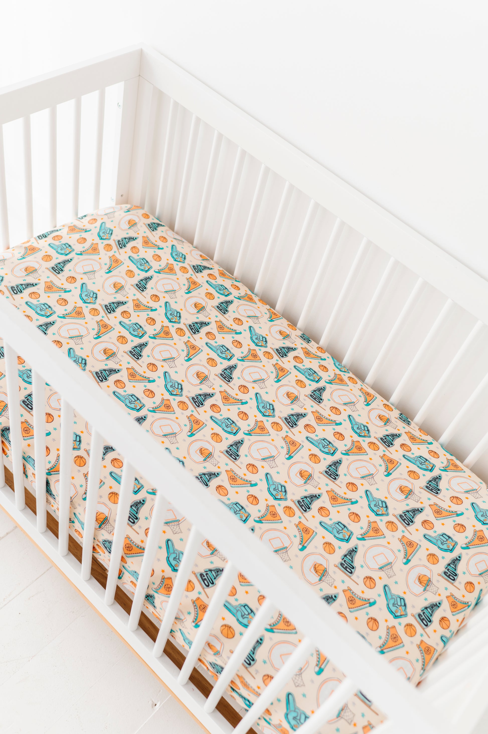 Crib with a bamboo fitted sheet featuring a sports theme