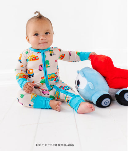 Baby in a colorful Leo the Truck bamboo convertible romper playing with a Leo the Truck plush toy on a white background