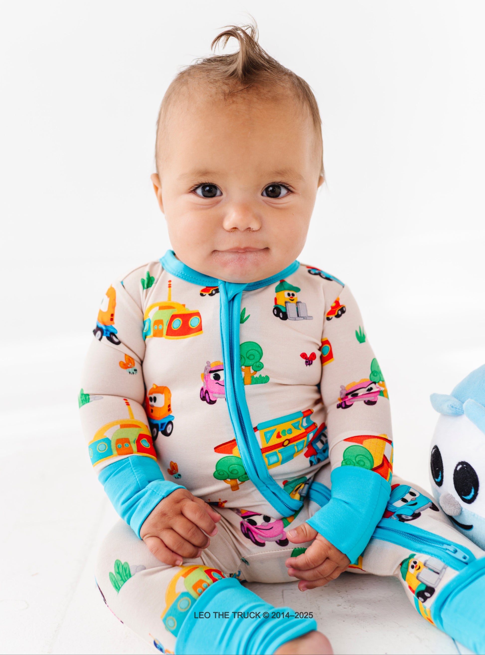 Baby wearing a colorful Leo the Truck bamboo onesie on a white background.