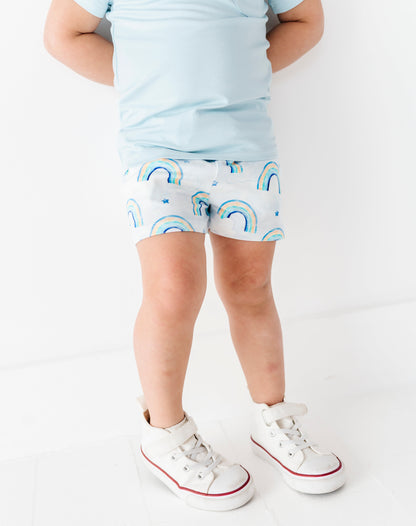 Child wearing light blue bamboo shirt and rainbow-patterned bamboo cotton shorts on a white background