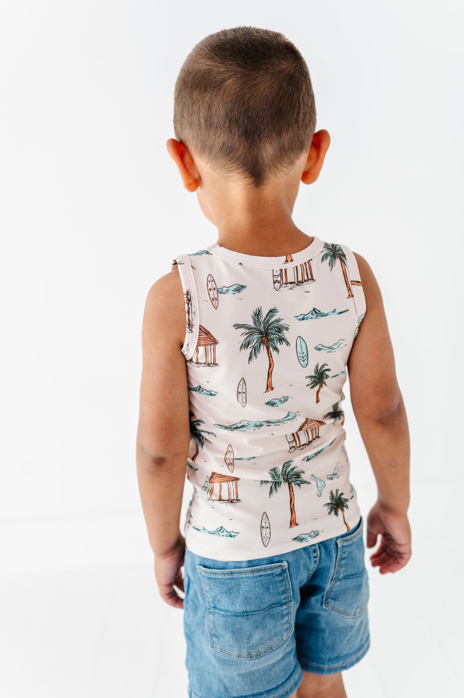 Child wearing a sleeveless shirt with a tropical pattern on a white background