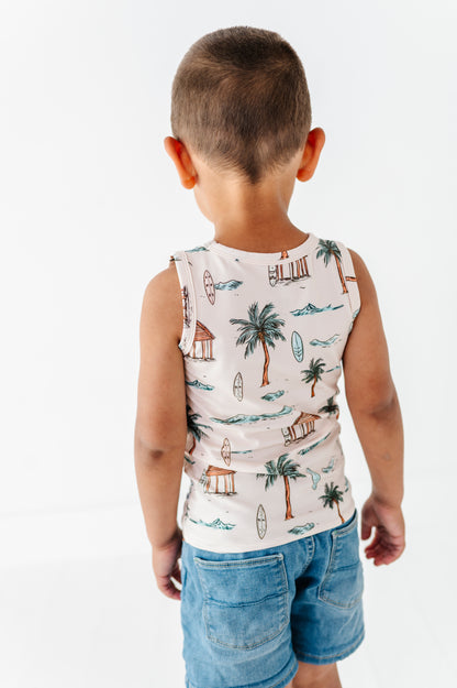 Child wearing a sleeveless shirt with a tropical pattern on a white background