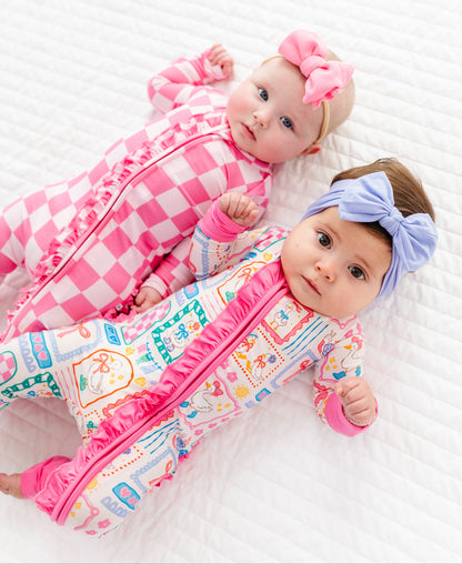 Two babies in colorful bamboo rompers with headbands on a white background
