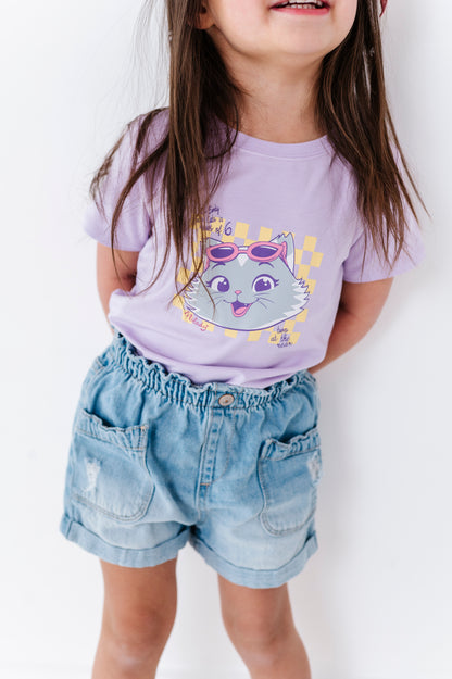 Child wearing a purple bamboo blend t-shirt with a 44 Cats graphic and denim shorts on a white background
